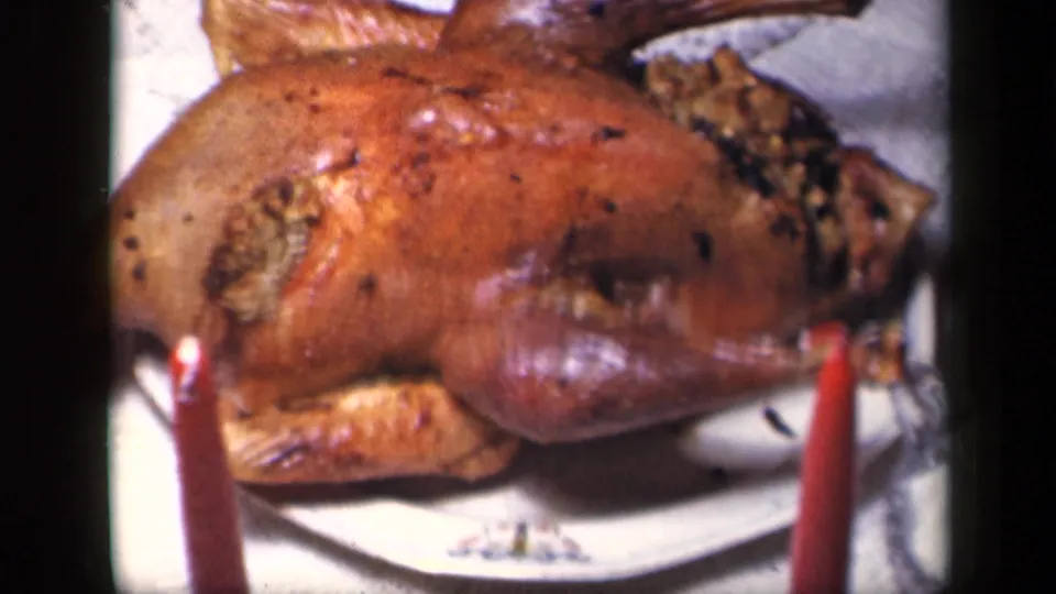 1942 Sebring, Ohio home-movie close-up of the holiday turkey, showing stuffing, browned skin, a white platter, and red candles.