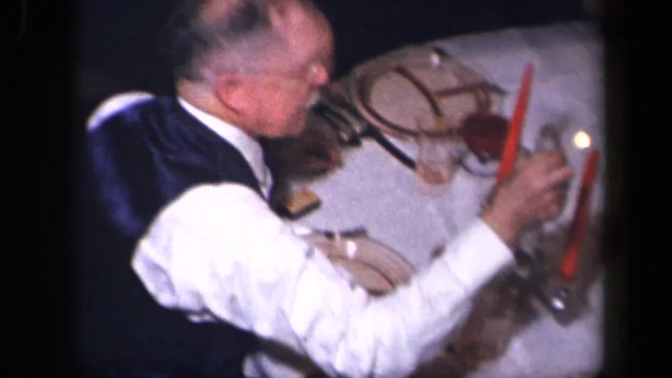 An older man in 1942 Sebring, Ohio appears to light a red candle beside the Thanksgiving table in an indoor family setting.