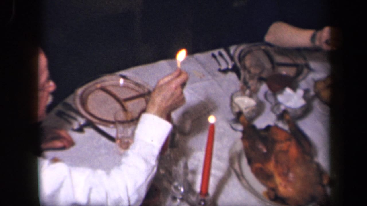 The 1942 Sebring home-movie frame shows a lit match, red candle, plates, glassware, and a roasted bird on the table.