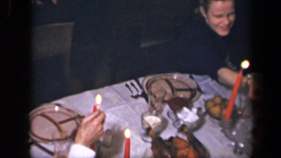 An adult woman smiles beside the formal table in Sebring, Ohio 1942 home-movie footage, with candles and dishes nearby.