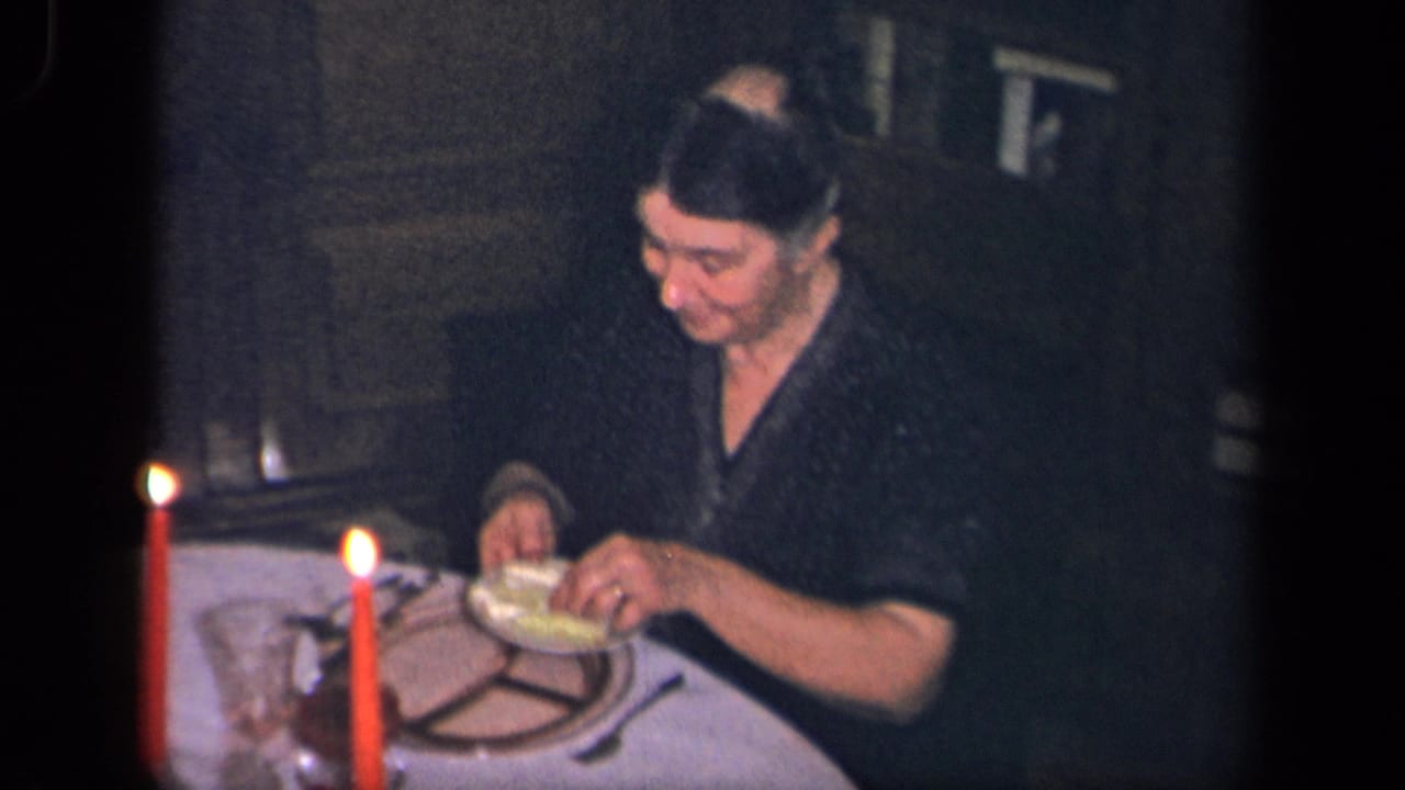 Woman seated at a candlelit dinner table with plates, glassware, and food.