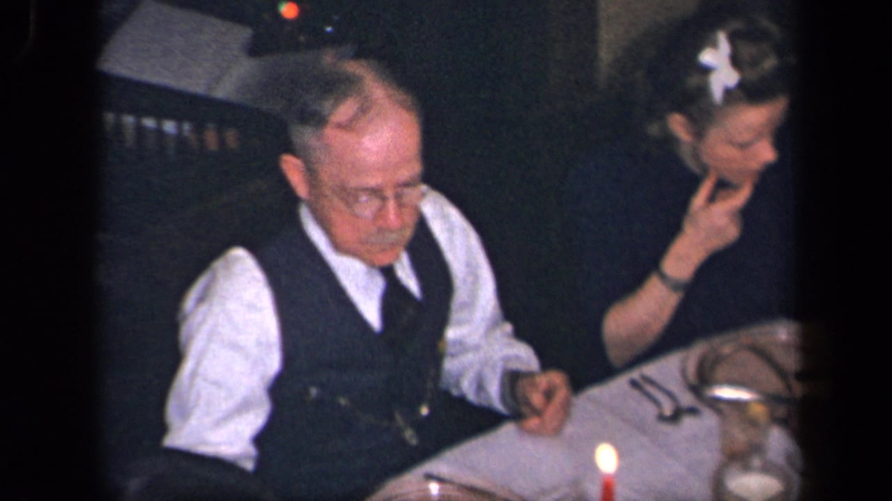 1942 Sebring, Ohio home-movie frame showing an older man in a vest and a woman seated at a formal candlelit dinner.