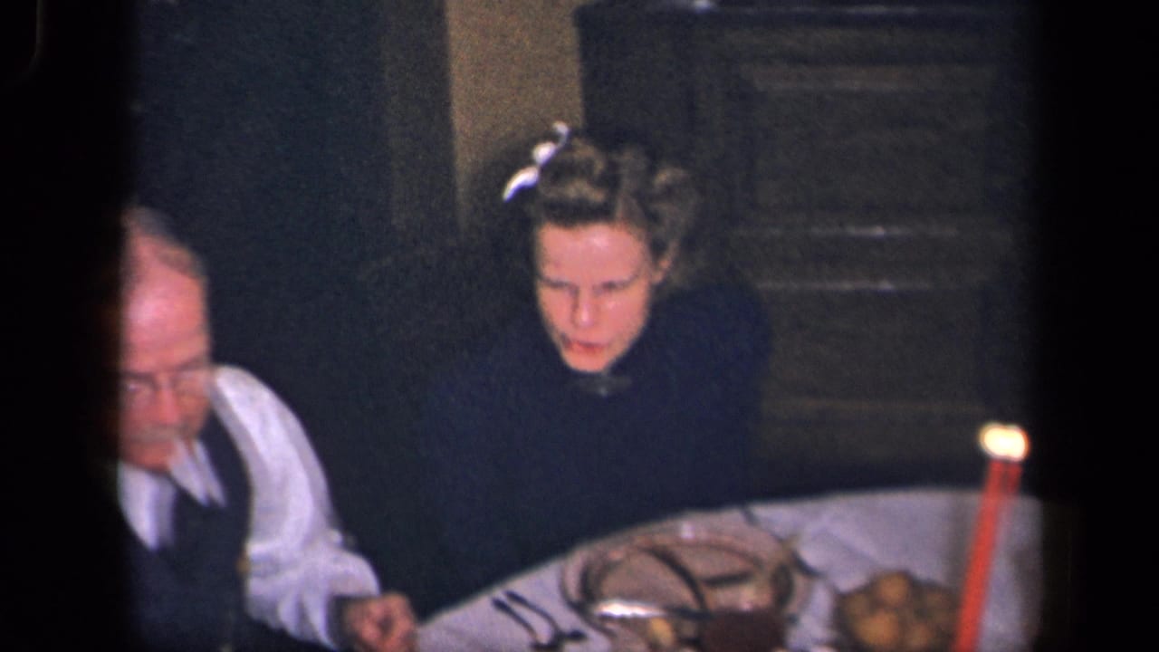 1942 Sebring, Ohio frame showing a woman and older man at a formal dinner table with a red candle, dishes, glassware, and potatoes.