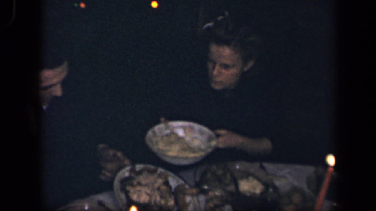 In Sebring, Ohio, 1942 home-movie footage, adults sit around a dim candle-lit table as food is served from shared dishes.