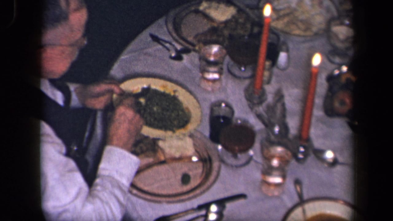 Overhead view of a man serving green vegetables at a candlelit dinner table.