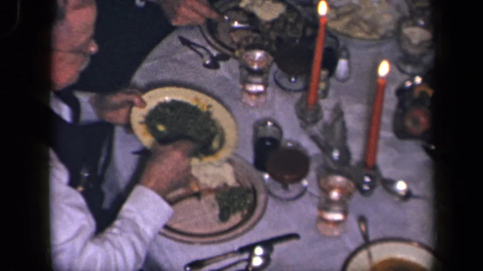 The final 1942 Sebring, Ohio frame shows a hand dishing vegetables at a candlelit table with plates, glasses, and utensils.
