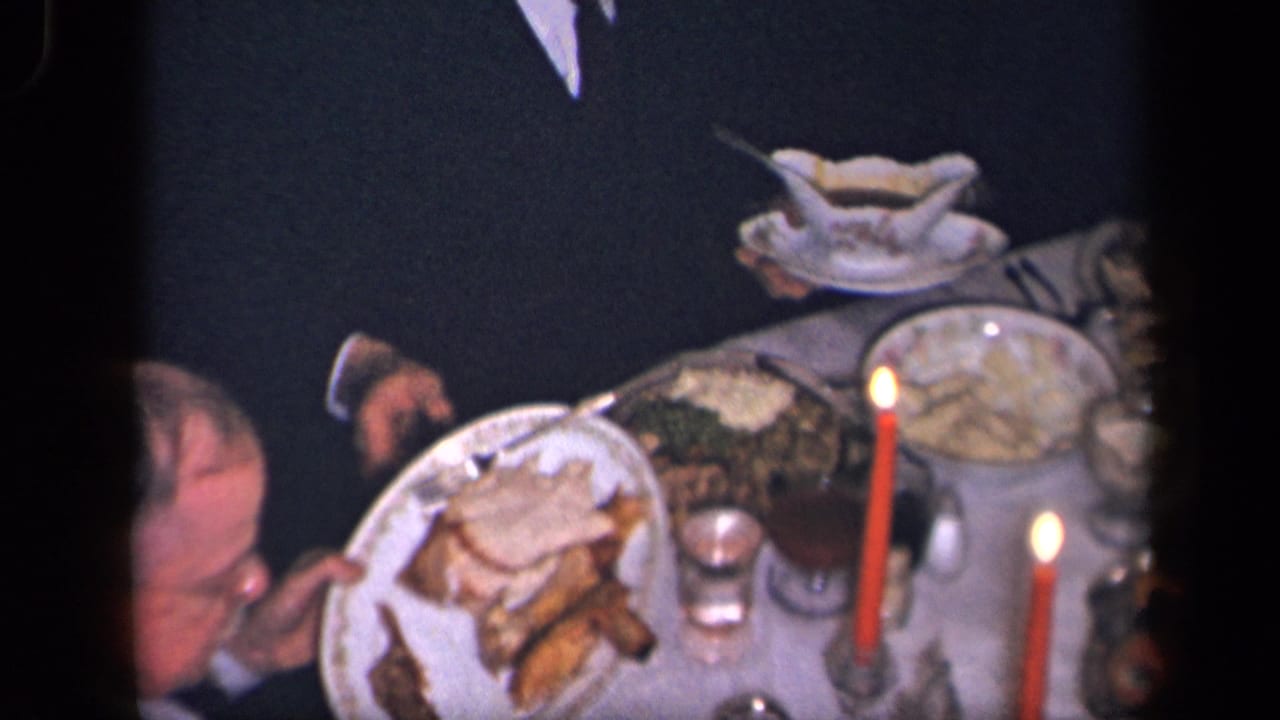 Overhead view of a dinner table with plates, candles, glassware, and a person partly visible.