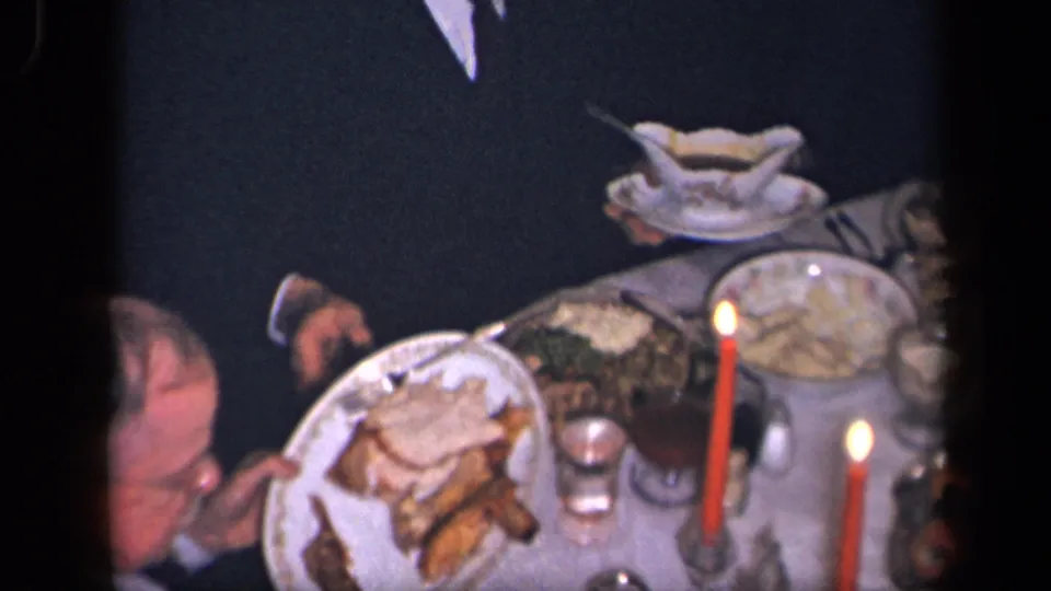 Candlelit 1942 Sebring, Ohio dinner table with plates of food, glassware, and a partially visible diner.
