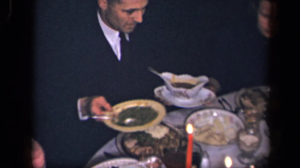 1942 Sebring, Ohio home-movie frame of a suited man seated at a formal candlelit family meal.