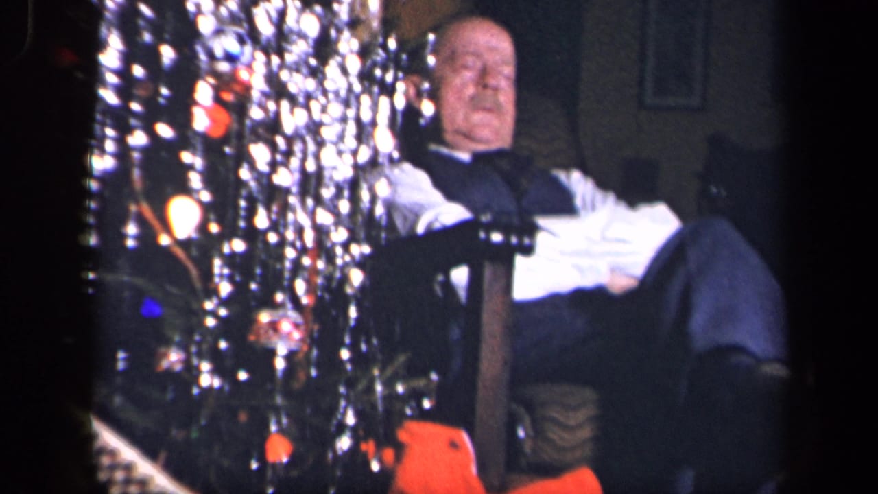 In a Sebring, Ohio 1942 home-movie frame, an older man sits near a decorated Christmas tree with bright tinsel and ornaments.