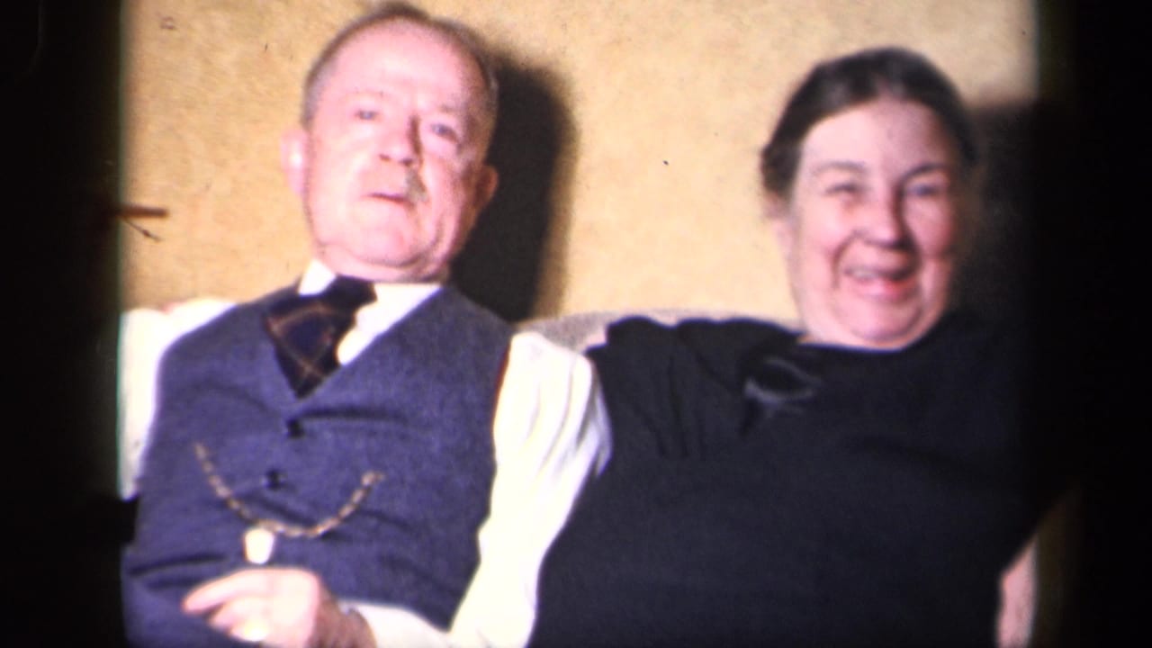 An older couple sits close together indoors in Sebring, Ohio, with the man wearing a vest and tie and the woman smiling in a dark dress.