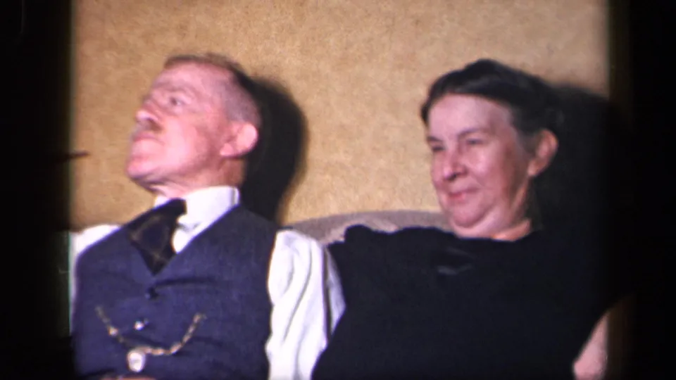An older couple sits close together in a Sebring, Ohio home, appearing relaxed in a softly exposed 8mm frame.