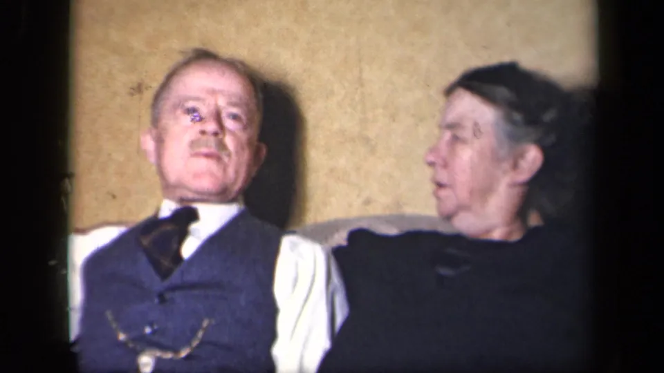 The man faces forward and the woman turns toward him in the Sebring, Ohio 8mm home-movie interior.