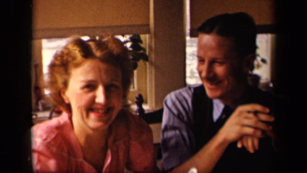 In the supplied 1942 Sebring, Ohio home-movie context, a smiling woman sits beside a man in a vest inside a warmly lit room.