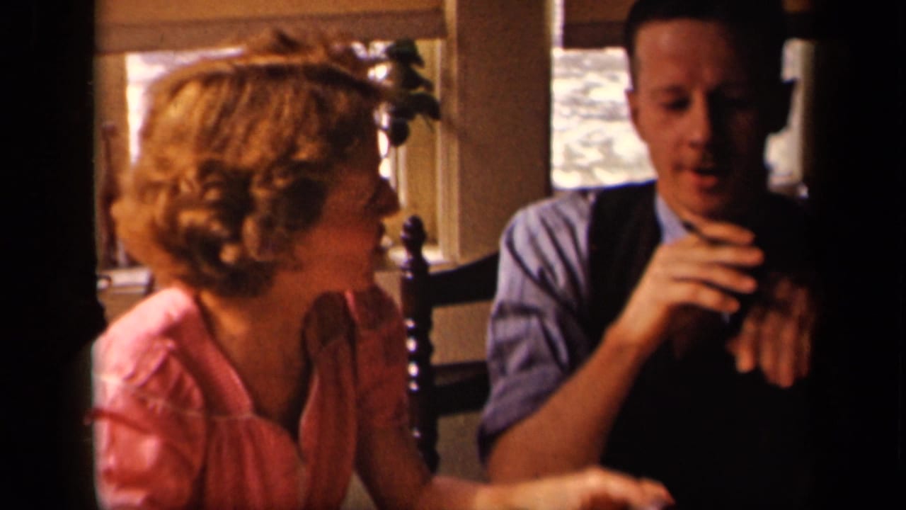 The woman turns toward the man with her hands near her face as he handles a cigarette in the indoor Sebring home setting.