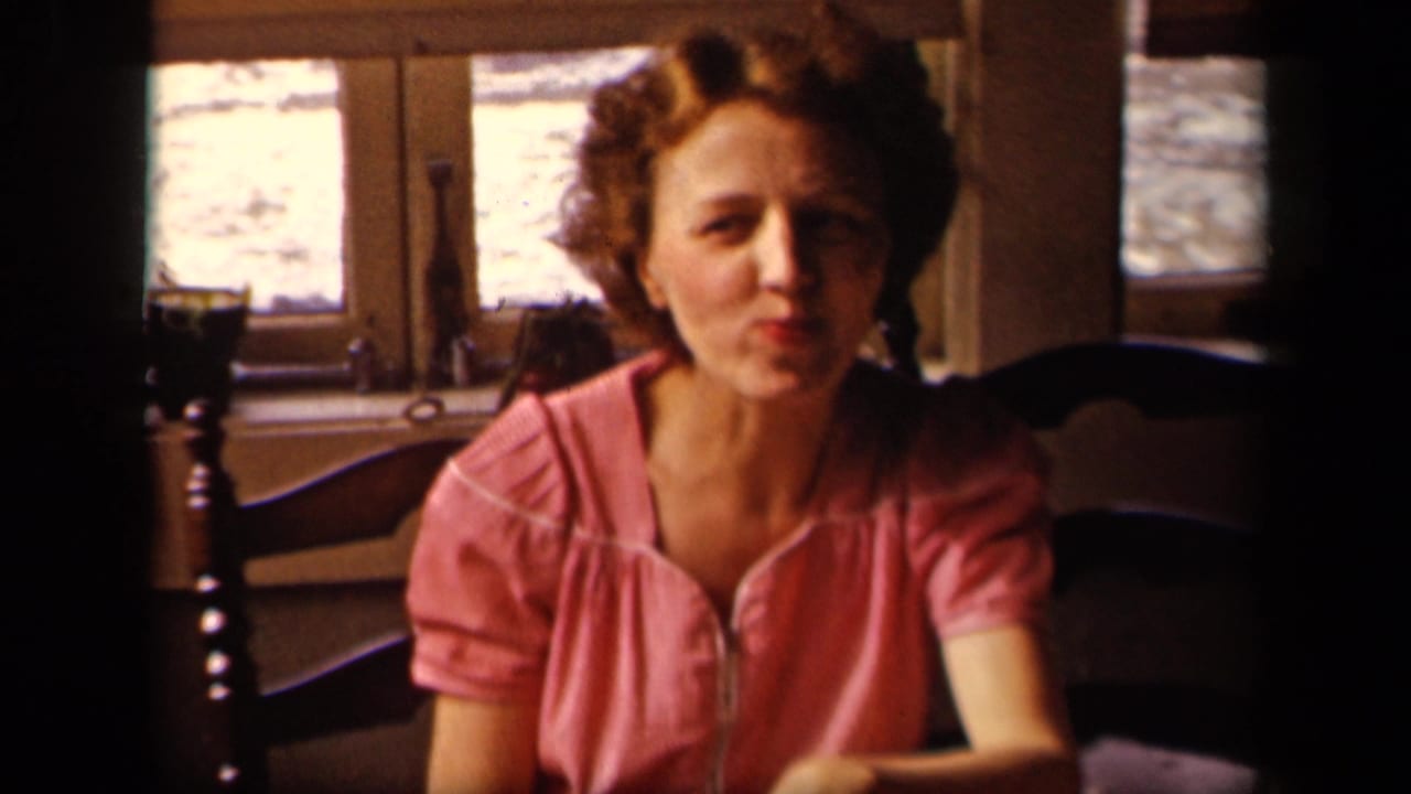 Young woman in a pink blouse sits at a table in a Sebring, Ohio home-movie interior from 1942, facing the camera.