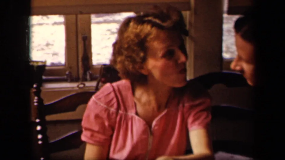 Young woman in a pink blouse turns toward a partially visible adult beside her in the 1942 Sebring, Ohio home movie.