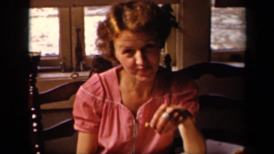 Young woman in a pink blouse looks toward the camera while holding food in a private Sebring, Ohio interior.