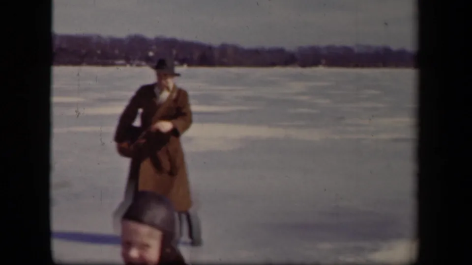 The man pauses or turns toward the camera on the frozen Sebring lake, with a bundled foreground figure partly blocking the lower frame.