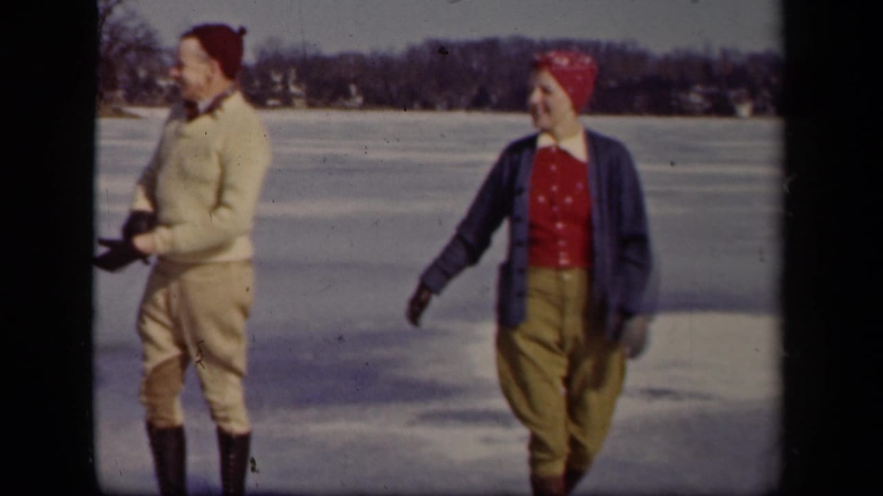 In metadata-supported Sebring, Ohio, 1942, a man and woman walk across a frozen lake in red winter headwear and gloves.