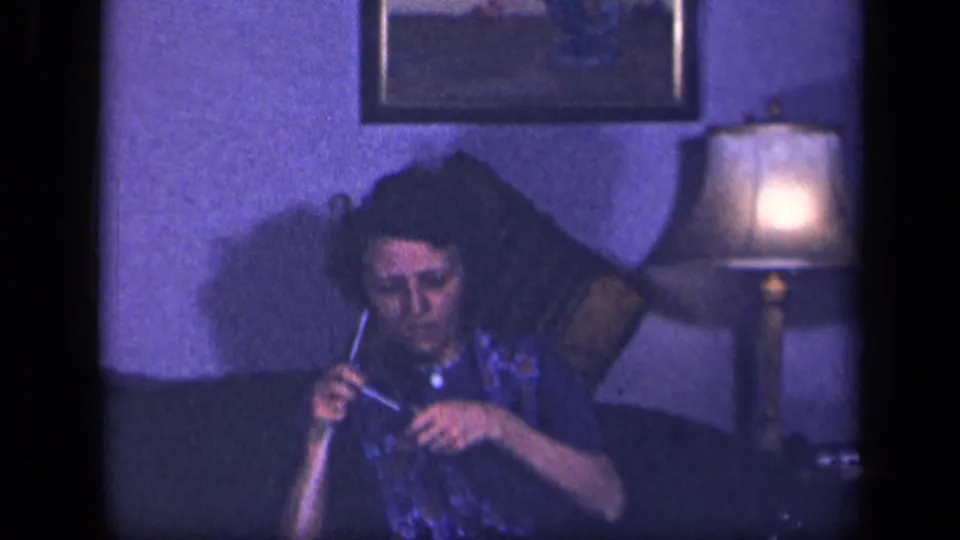In a 1942 Sebring, Ohio home-movie frame, a woman sits on a couch with knitting needles near a glowing table lamp.