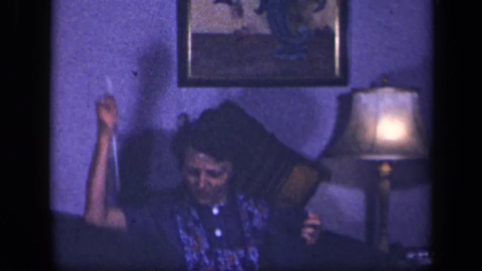 The woman lifts one knitting needle in a playful gesture while seated in the Sebring, Ohio living room.