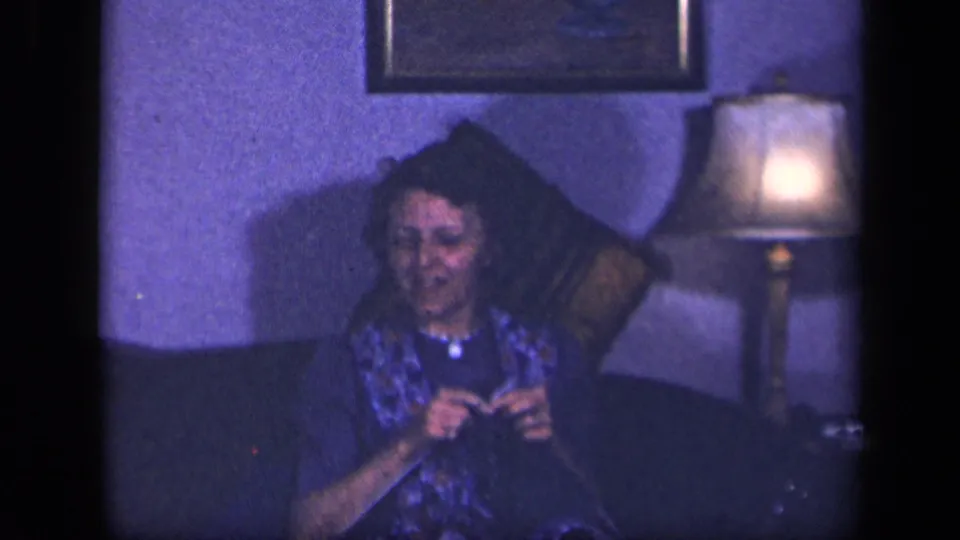 A closer 1942 Sebring frame shows the woman looking down at her handwork on the couch, with the lamp and framed picture behind her.