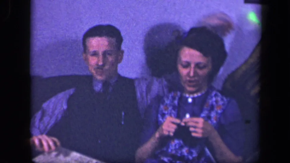 The couple remains seated on the sofa in the Sebring home interior, with the woman knitting and motion visible behind her shoulder.