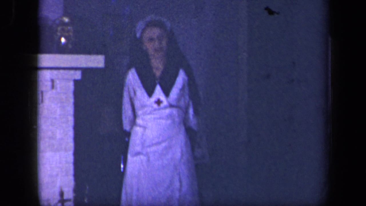 In 1942 Sebring, Ohio home-movie footage, a woman in a nurse-style uniform stands near a stone fireplace in a dark blue-purple interior.