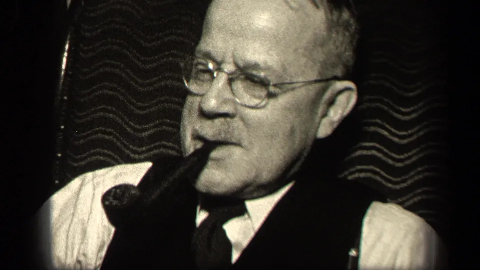 Older man in a vest and tie smokes a pipe in 1942 Sebring, Ohio home-movie footage, with soft focus and visible film grain.