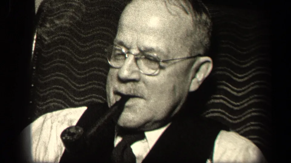 Sebring, Ohio 1942 close-up of an older man with glasses, mustache, vest, and pipe against dark wavy wallpaper.