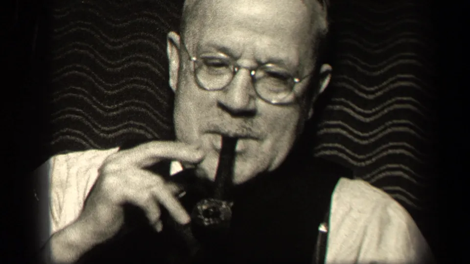 1942 Sebring, Ohio home-movie close-up of an older man adjusting or holding his pipe while wearing glasses and a vest.