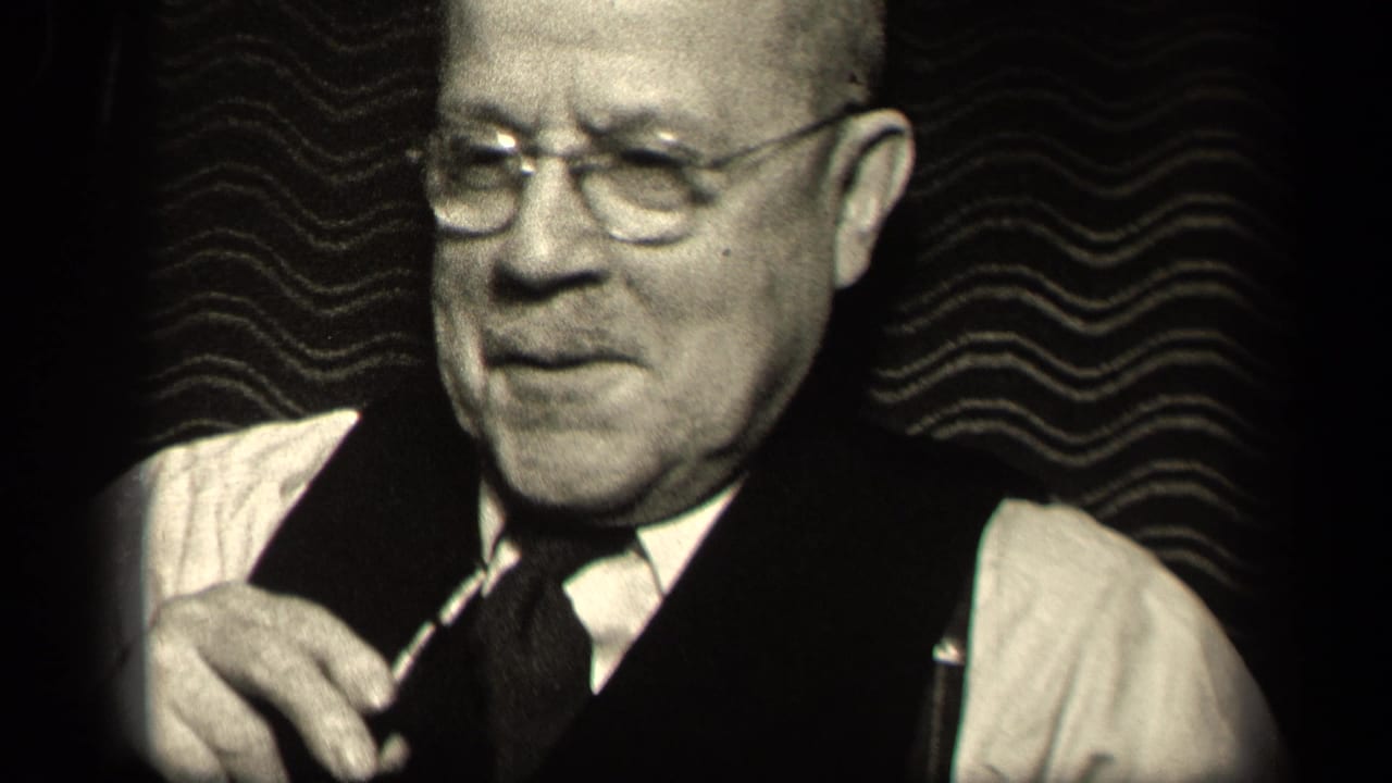 Older man in glasses, vest, and tie sits indoors in black-and-white 8mm footage from Sebring, Ohio, 1942 metadata.