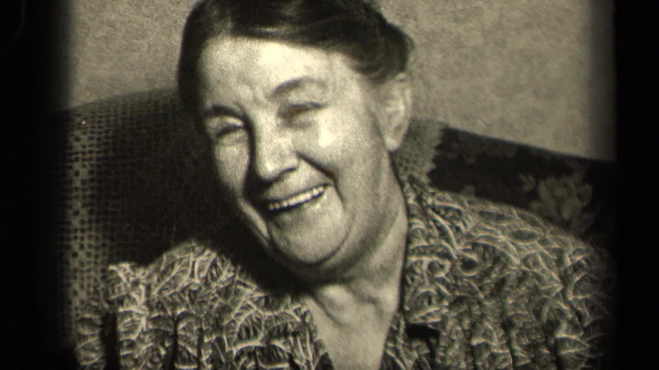 Older woman in a patterned blouse leans while laughing in black-and-white 8mm footage associated with Sebring, Ohio, 1942 metadata.
