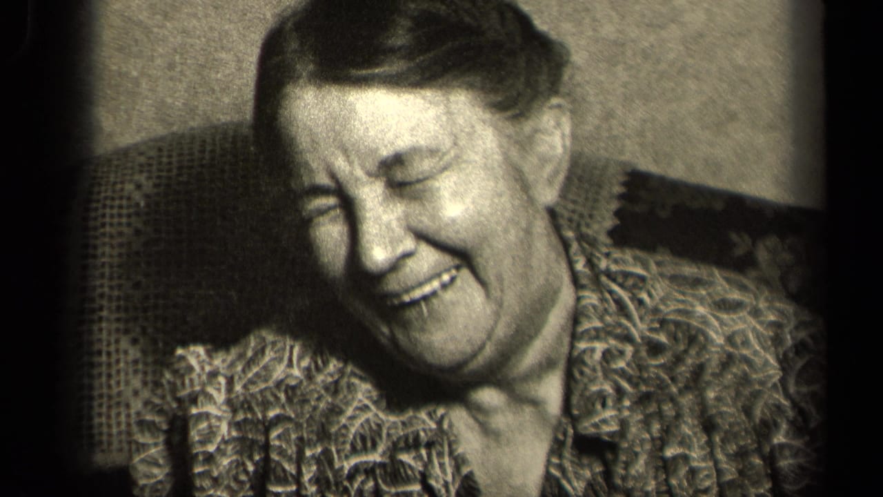 In a 1942 Sebring, Ohio 8mm home movie frame, an older woman laughs while seated in a patterned armchair indoors.
