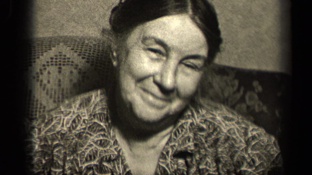 1942 Sebring, Ohio home-movie frame showing an elderly woman smiling toward the camera in a patterned dress and upholstered chair.