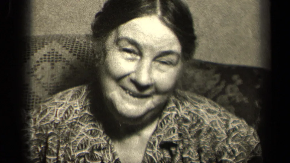 1942 Sebring, Ohio home-movie still with the woman smiling broadly from a close interior chair setting.