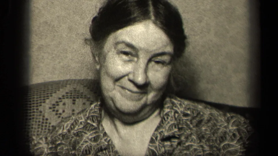 1942 Sebring, Ohio frame showing the woman looking toward the camera with a small smile in a grainy indoor home movie.