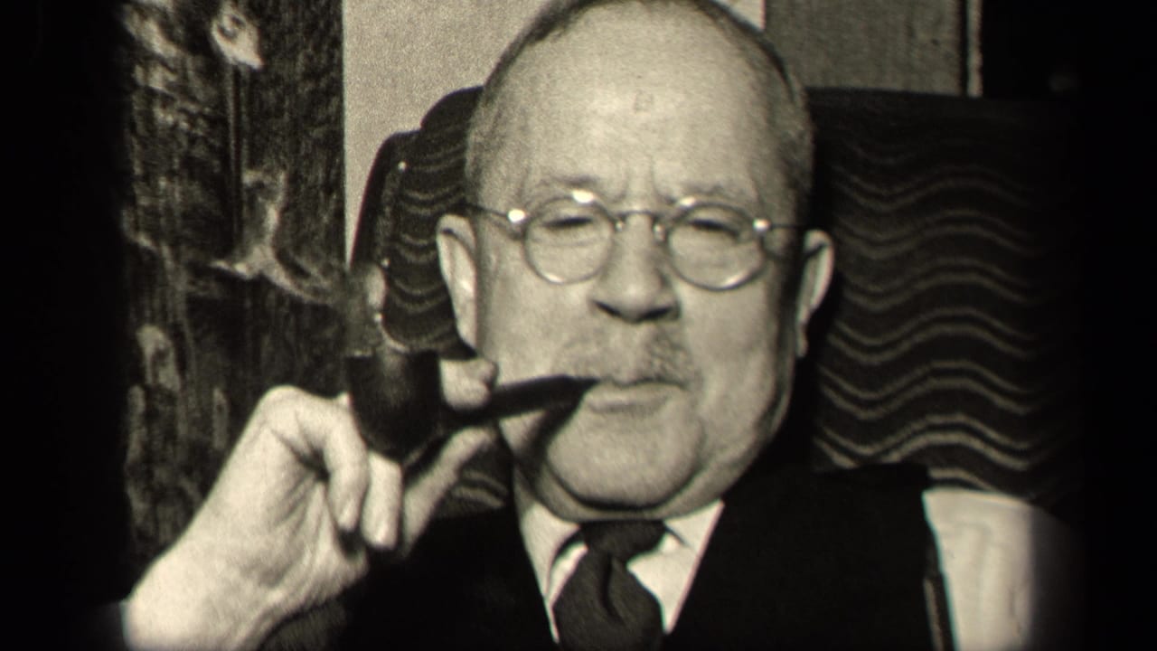 In 1942 Sebring, Ohio footage, an older man in a suit and round glasses faces the camera while holding a pipe near his mouth.