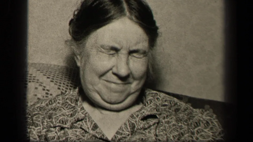 In Sebring, Ohio 1942 home-movie footage, an older woman in a patterned blouse sits on a textured couch with her eyes shut.