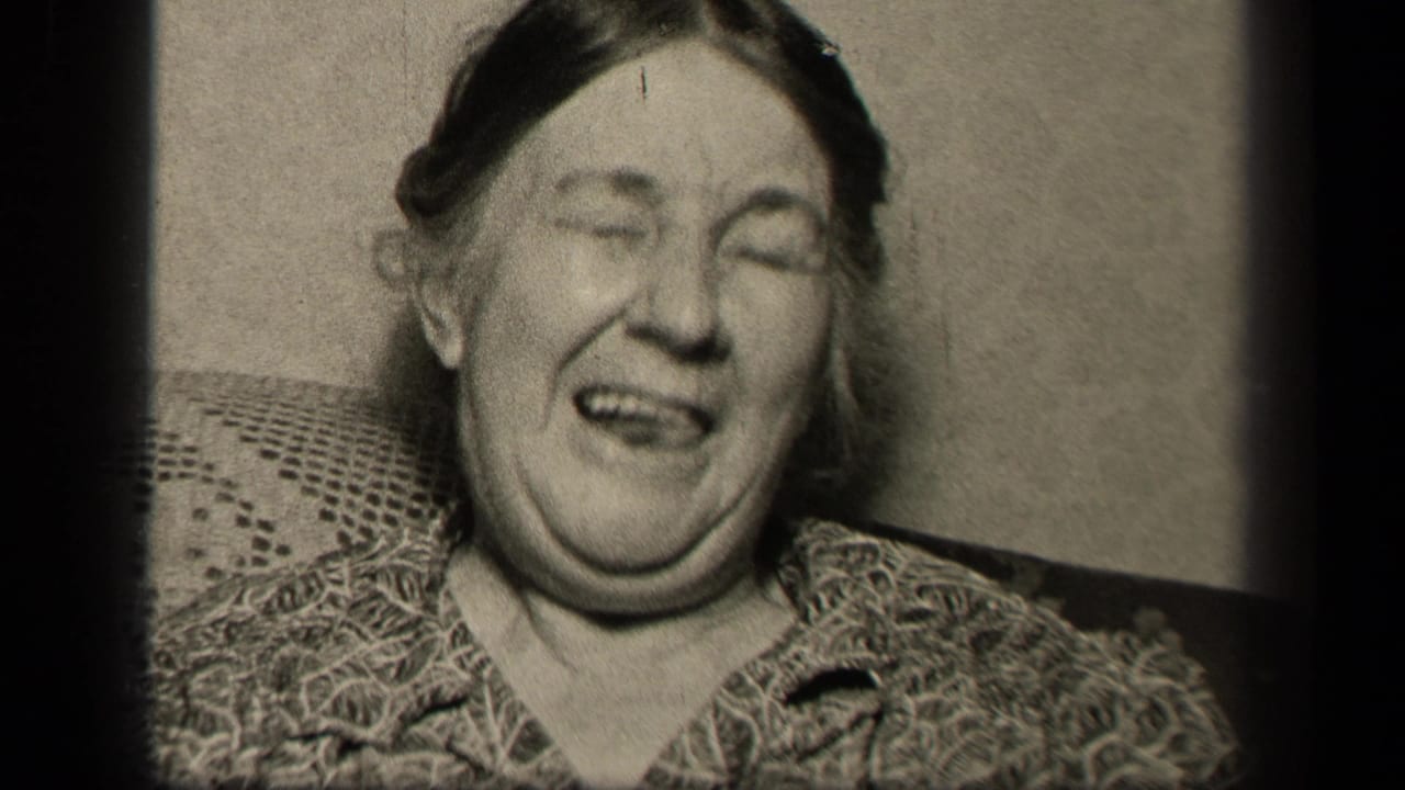 The older woman appears mid-laugh or mid-reaction, seated against a couch in the 1942 Sebring, Ohio home-movie frame.