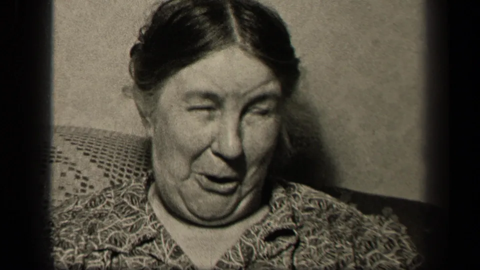 A close 8mm frame shows the seated older woman in Sebring, Ohio with a squinting, puckered expression.