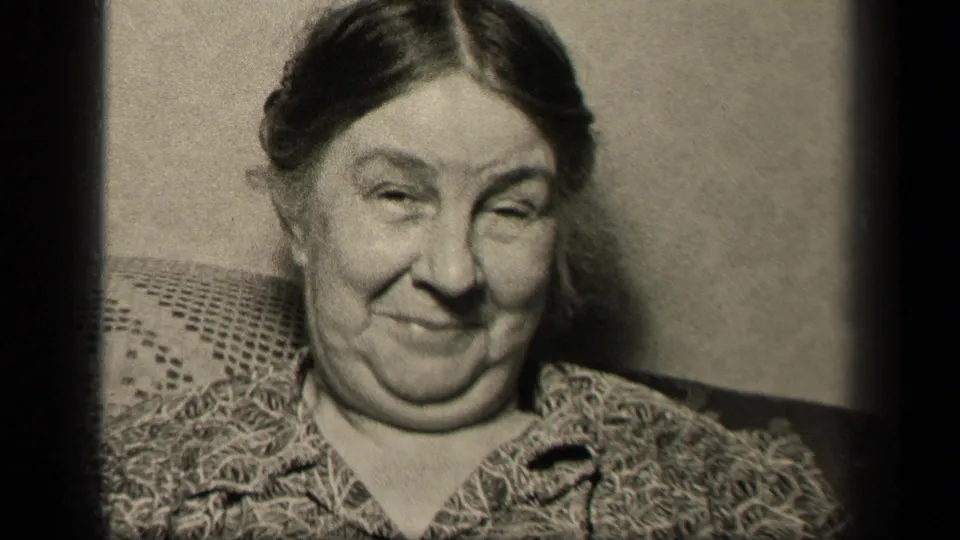 The Sebring, Ohio home-movie shot ends on the older woman seated on the couch with a restrained smile and narrowed eyes.