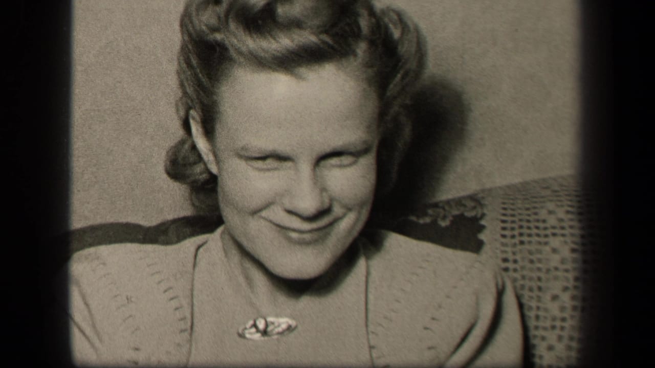 Younger woman in a light sweater smiles with her eyes narrowed while seated indoors.