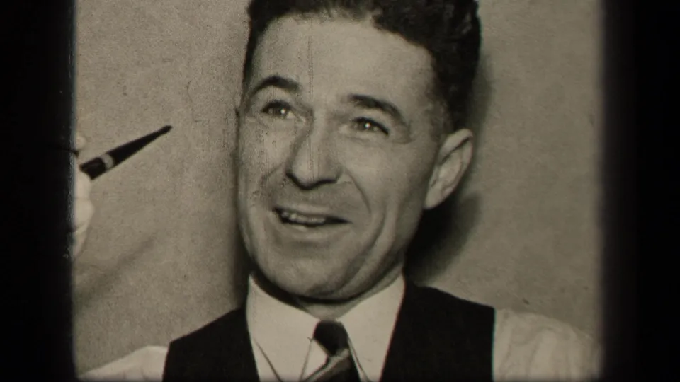 A man in a vest and tie holds a pipe near his face in supported 1942 Sebring, Ohio home-movie footage.