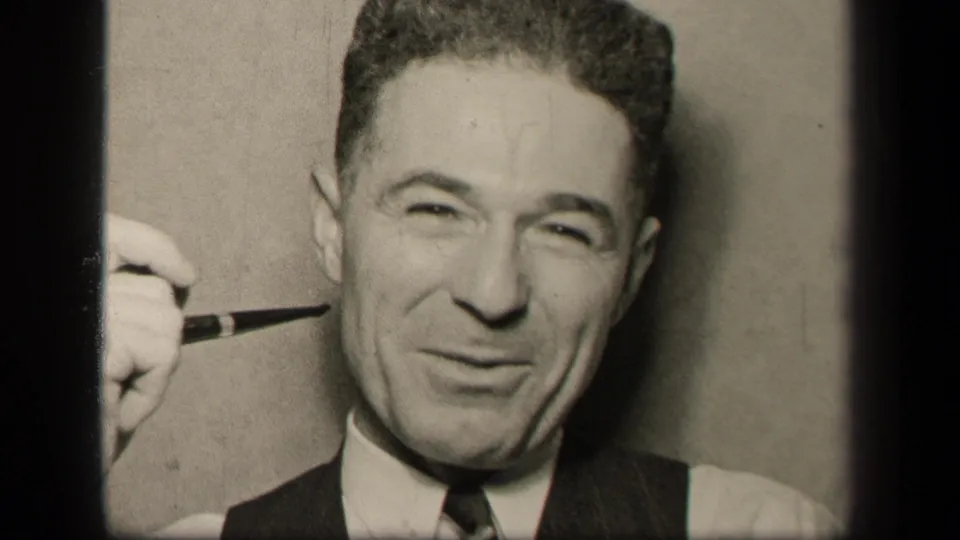 The Sebring, Ohio 1942 frame shows the man facing the camera with a pipe raised beside his cheek, wearing a white shirt, tie, and dark vest.