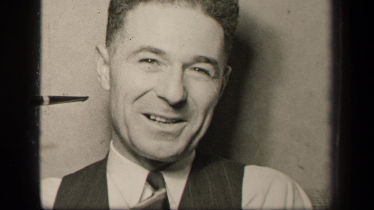 In 1942 Sebring, Ohio footage, a well-dressed adult man in a vest and tie smiles toward the camera in a domestic interior.