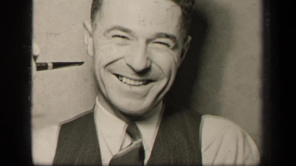 A close 8mm frame shows the well-dressed man laughing toward the camera in the Sebring, Ohio domestic scene.