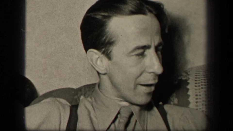 A 1942 Sebring, Ohio home-movie frame shows the man in side view, appearing to speak or listen while seated against a sofa.