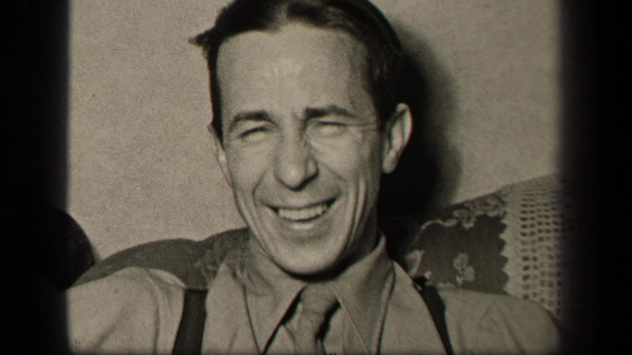 Adult man laughs broadly while seated indoors in close-up.